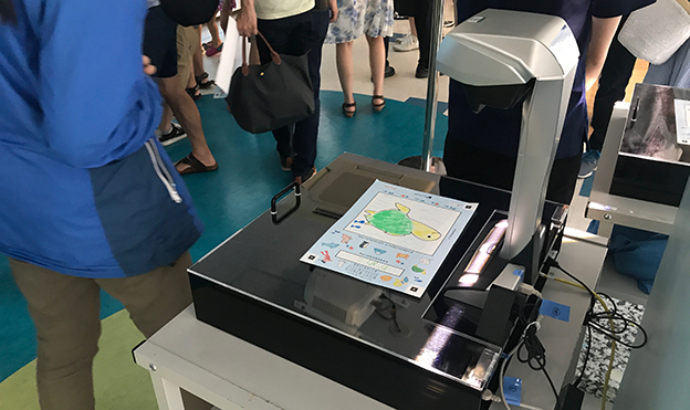 画像：お客様に自由に描いていただいた絵をスキャンして、映像内に取り込む。取り込んだ後の絵は、お持ち帰りいただける。