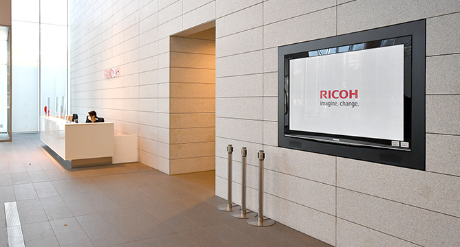 オフィスの受付の壁に設置されているデジタルサイネージ